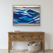 Artist_Shilo_Ratner_Ebb_and_Flow_36in_x_48in, Wooden console table with a basket of pillows below an abstract blue painting on a white wall.