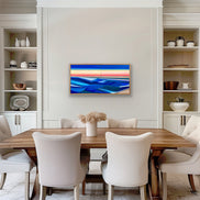 Artist Shilo Ratner painting Rise 20in x 40in, Modern water abstract painting of sunset with blue and red hues on a beige wall, Dining room with a wooden table and white chairs, featuring a colorful abstract painting on the wall.