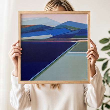 Original Abstract Mountain Painting Whisper of the Wild the painting features geometric shapes in shades of blue, navy, green, and pale pink, set in a light wood frame by Artist Shilo Ratner. 